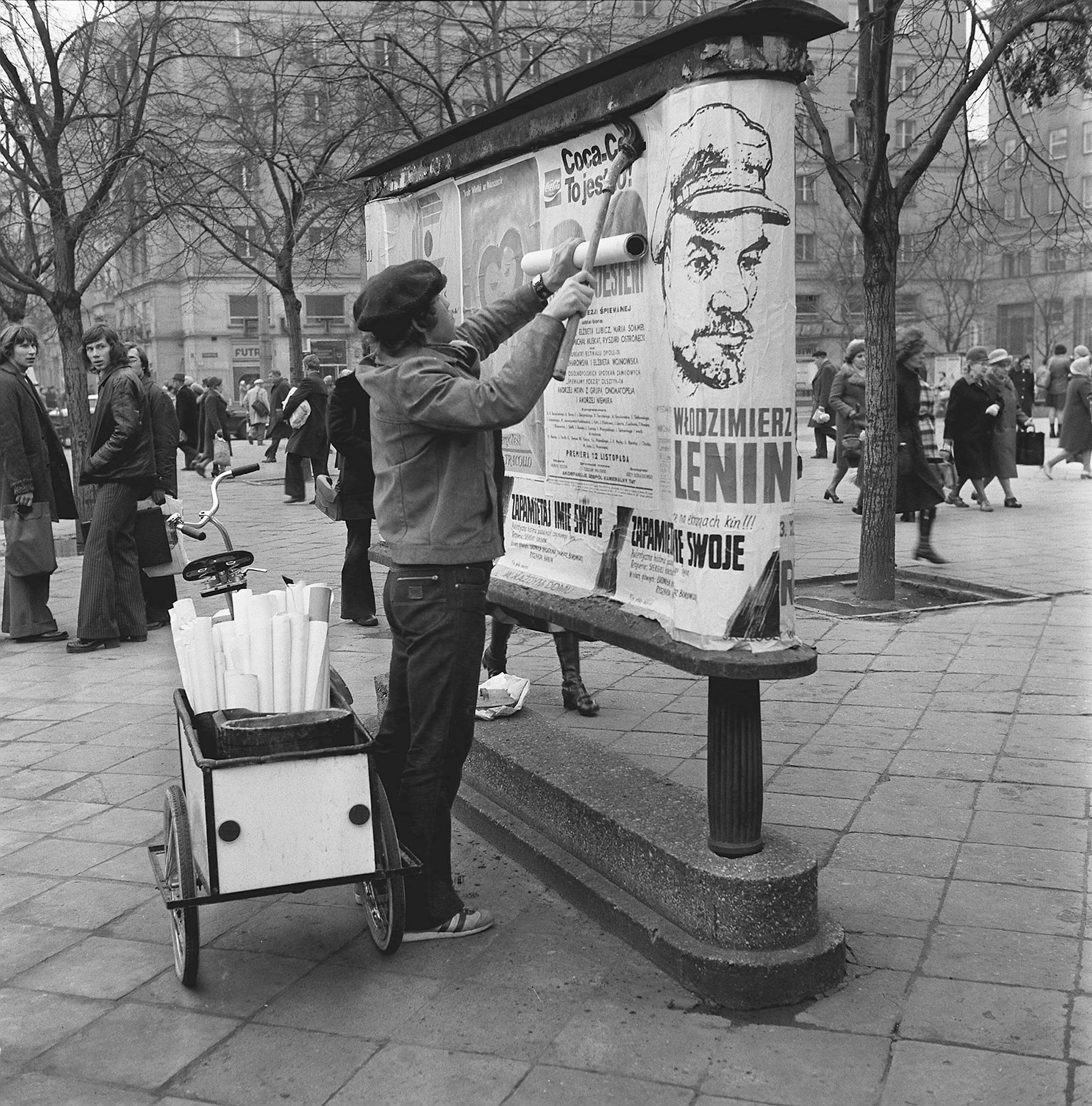 Mężczyzna rozklejający plakat z hasłem reklamowym (fot. PAP/CAF/Andrzej Rybczyński)